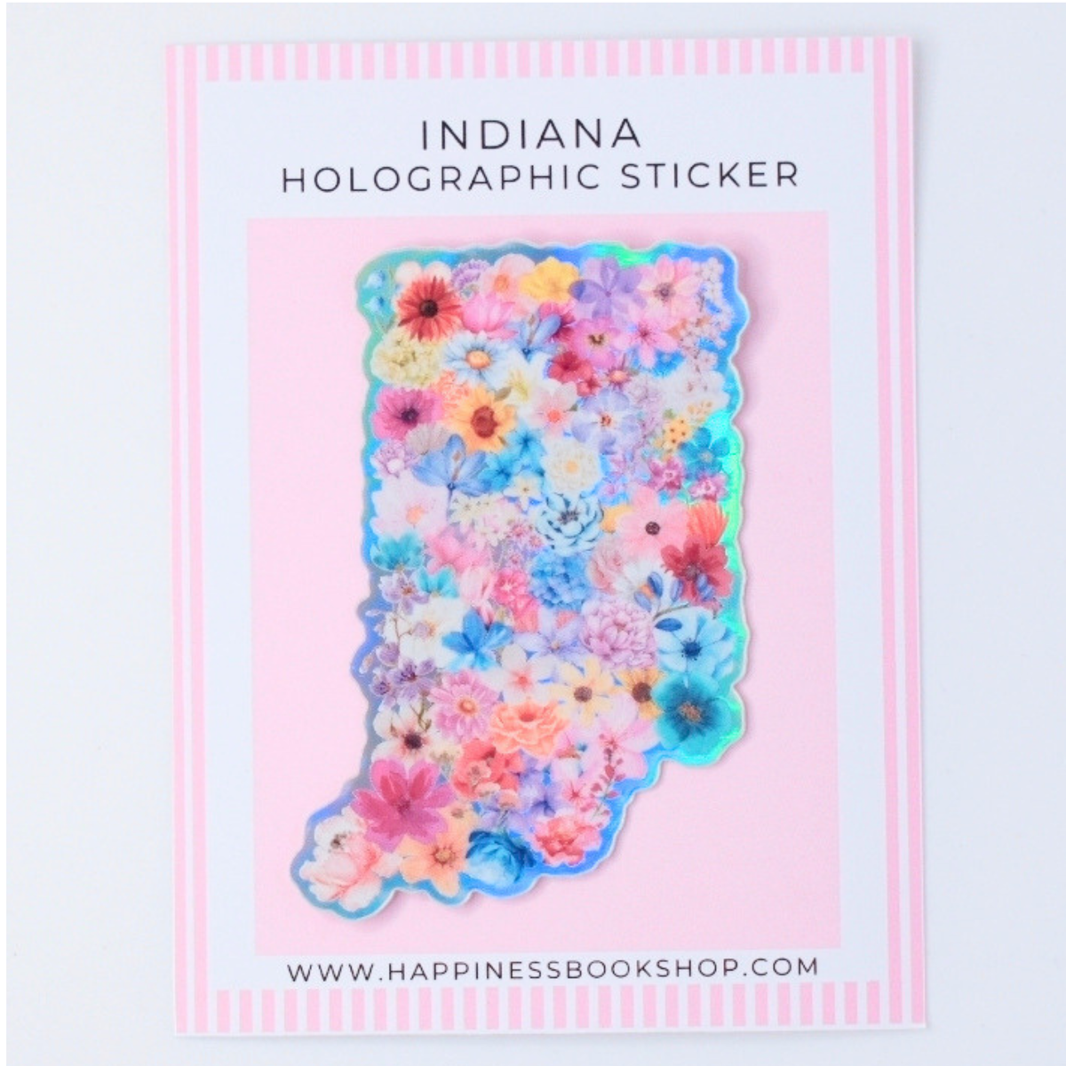 Indiana-shaped holographic sticker covered in colorful pressed flowers, displayed on a pink card with the text 'INDIANA HOLOGRAPHIC STICKER' and the website 'WWW.HAPPINESSBOOKSHOP.